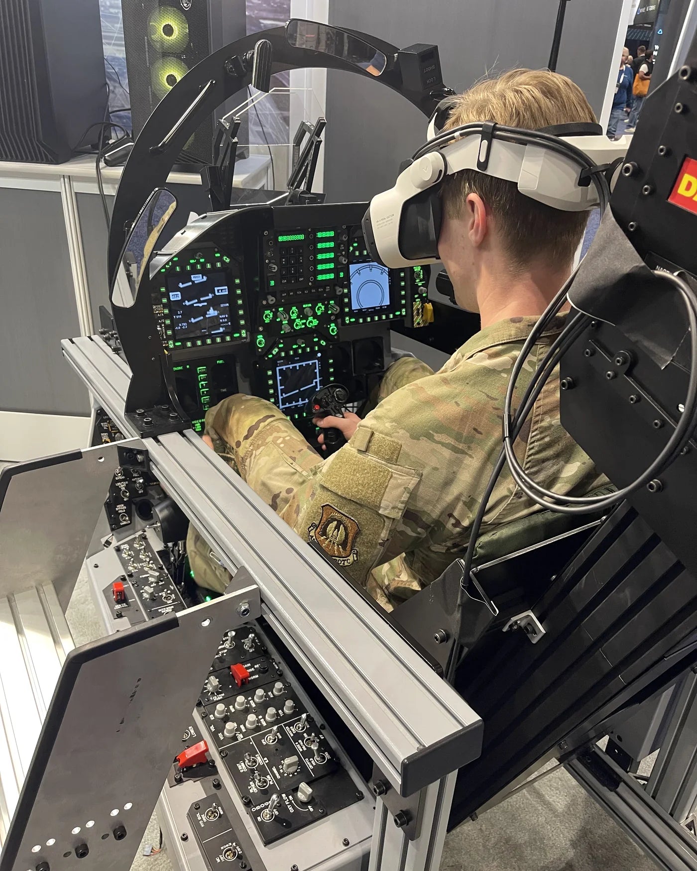 Uniformed I/ITSEC 2025 attendee operating the Dogfight Dynamics cockpit in virtual reality